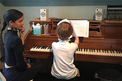 Woman teaching young boy piano